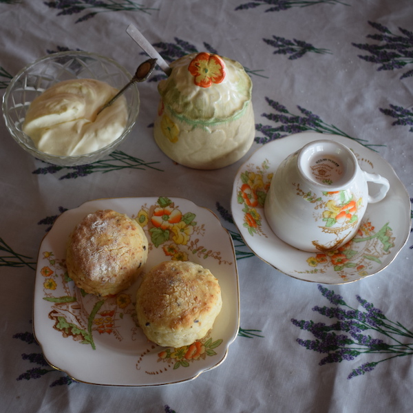 Scones on plate, cream, jam pot, tea cup and saucer.